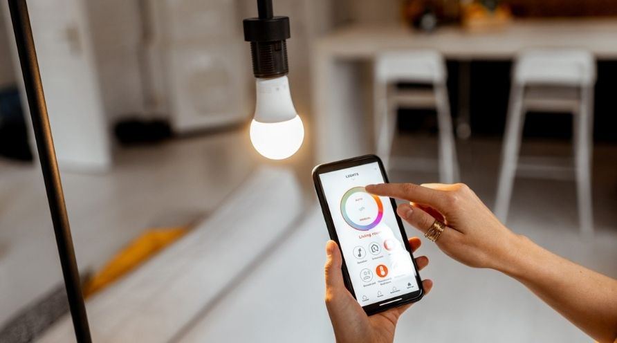 Woman using her phone to control a smart light bulb