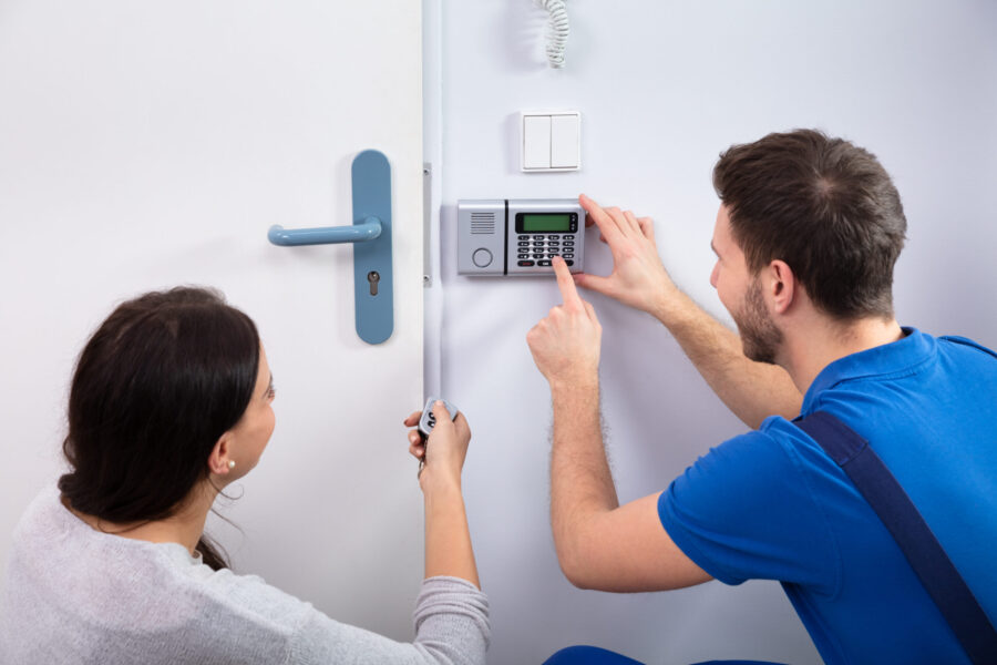 A technician showing a woman a security key pad on her door