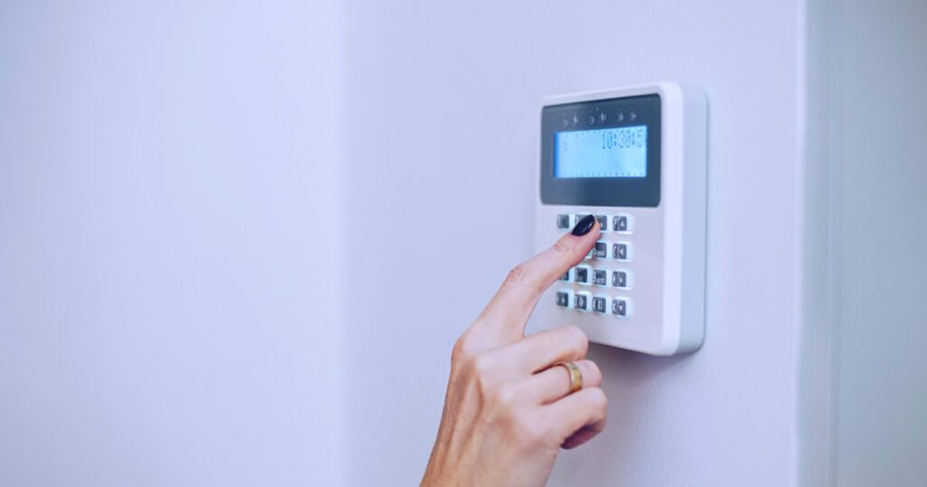 Close-up of a woman's hand entering a code on a security keypad.